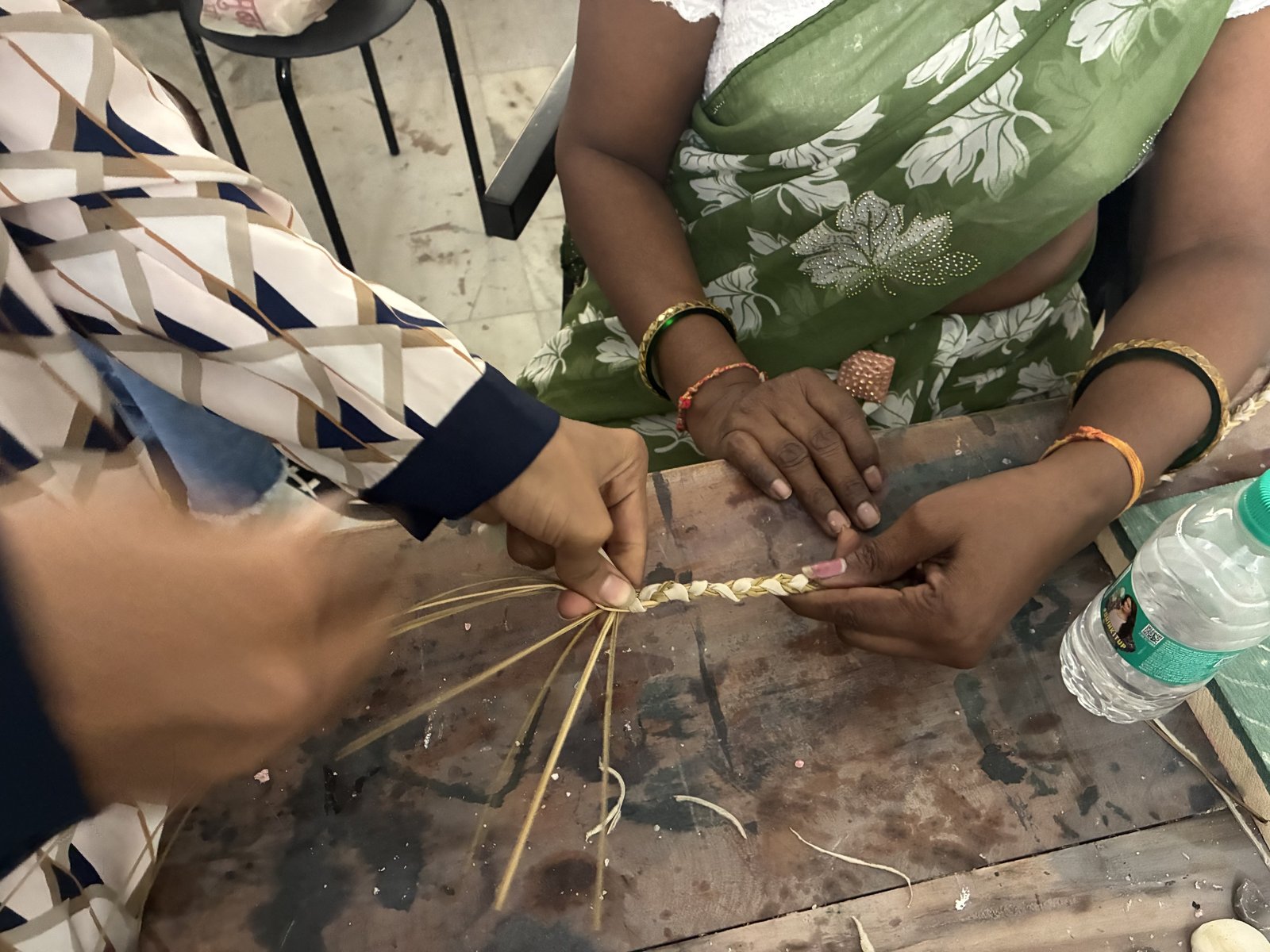 Close-up of artisan hands weaving natural fibers and leather offcuts